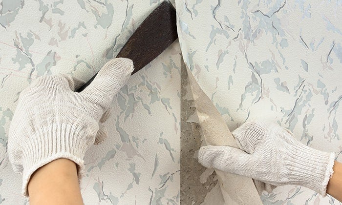 How to remove wallpaper Gloved hands remove wallpaper using a scraper tool