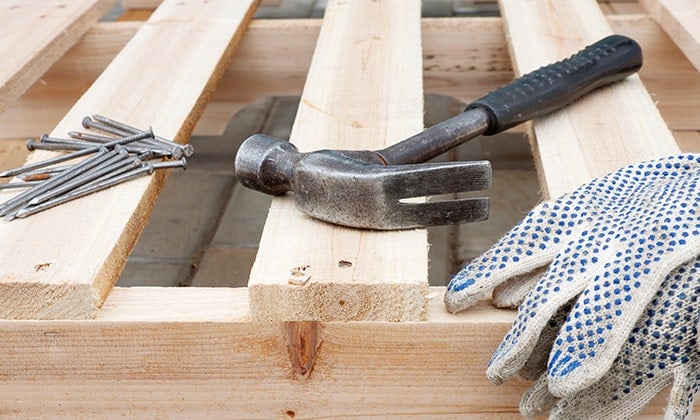 how to take apart a pallet Nails, hammer and gloves resting on a pallet