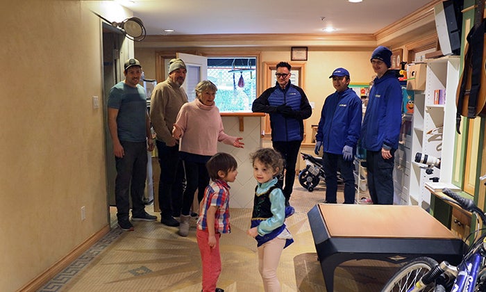 Une femme et sa famille sont heureux et surpris de leur nouvel espace désencombré, alors que le fondateur de 1-800-GOT-JUNK?, Brian Scudamore et deux équipiers se tiennent à ses côtés. 