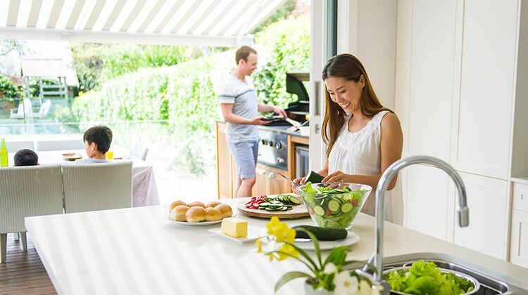 Woman preparing salad in kitchen that connects to an outdoor patio