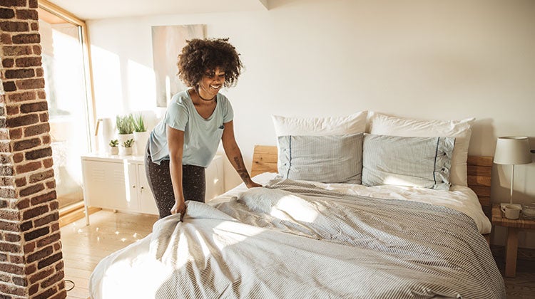 Woman arranging bedsheets in the guest bedroom