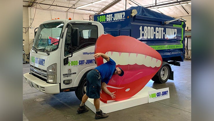 1-800-GOT-JUNK? truck team member pretending to be eaten by a large cardboard mouth