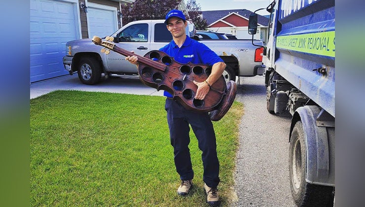 1-800-GOT-JUNK? team member holding a violin wine rack as a guitar