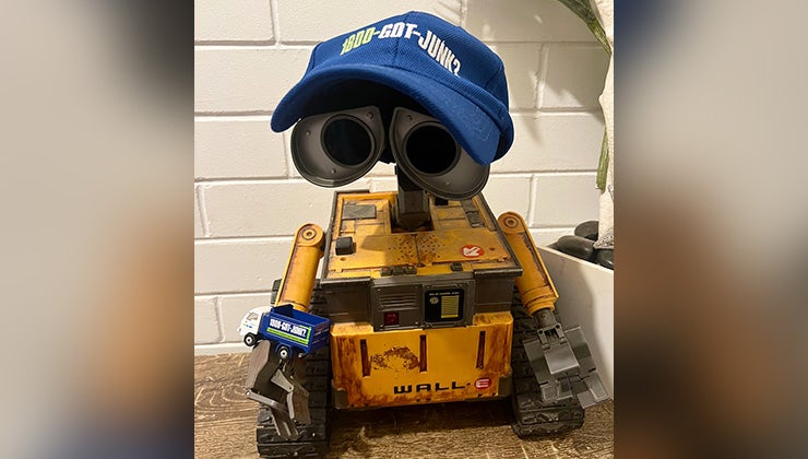 Wall-E figurine wearing a 1-800-GOT-JUNK? hat and holding a toy truck