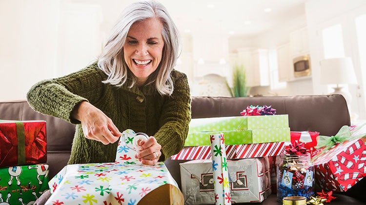 Woman wrapping holiday gifts on the couch