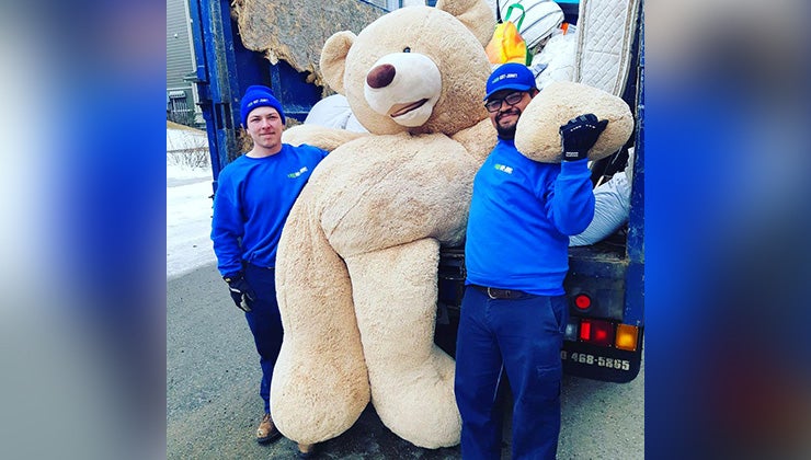Two 1-800-GOT-JUNK? truck team members holding up a giant teddy bear