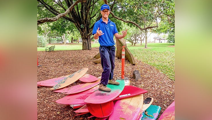 1-800-GOT-JUNK? Team Member posing on a stack of surfboards