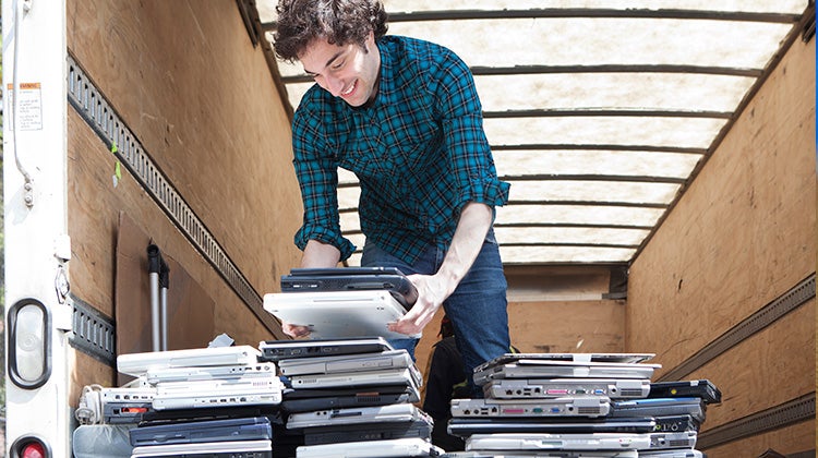 A man arranging old computers and laptops ready to be disposed of
