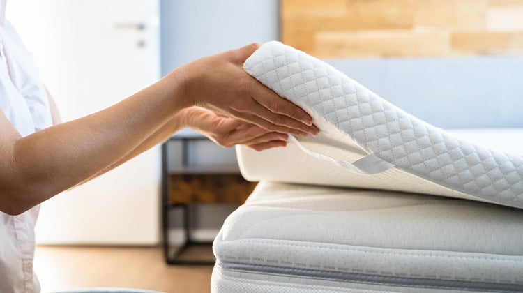 Person lifting up the mattress topper from their mattress