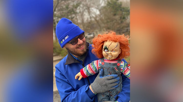 1-800-GOT-JUNK? team member holding a Chucky doll