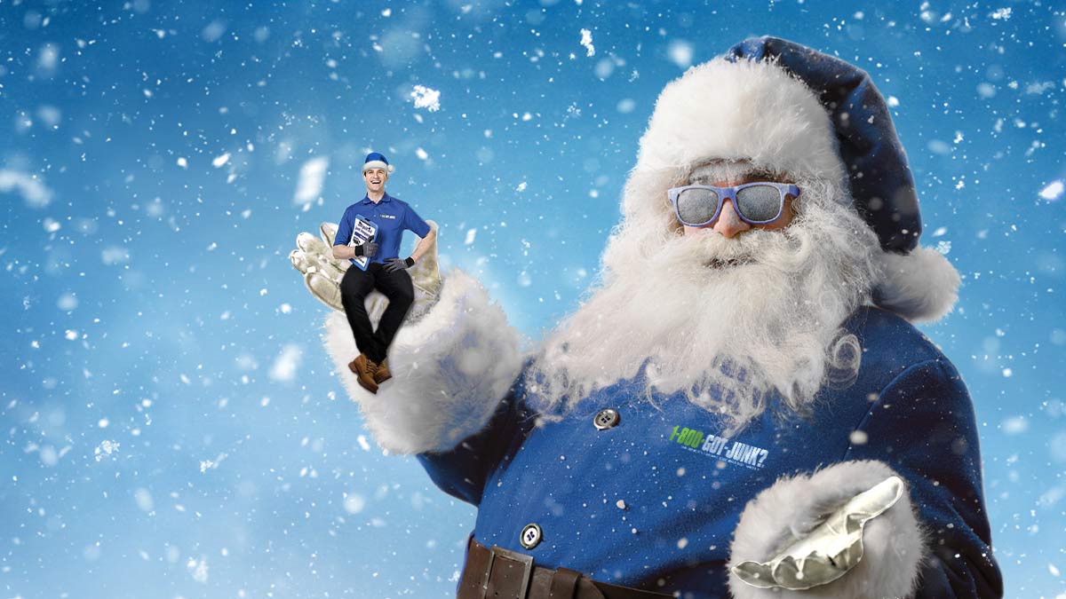 Junk Santa in a blue suit holding a small 1-800-GOT-JUNK? team member