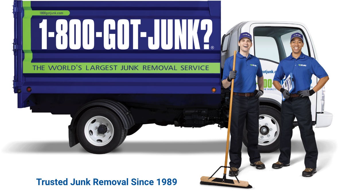 Two 1-800-GOT-JUNK? employees smiling in front of a 1-800-GOT-JUNK? truck, with the words 'Trusted Junk Removal Since 1989' underneath.