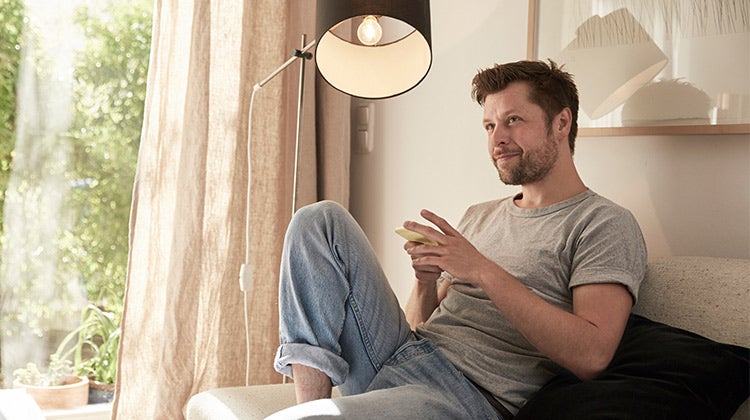 Man sitting next to a bright window with a reading lamp on