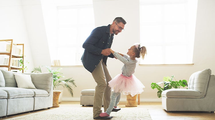 Father and daughter dancing in a clean living room