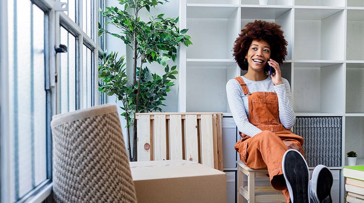 Woman smiling on the phone with moving boxes around her