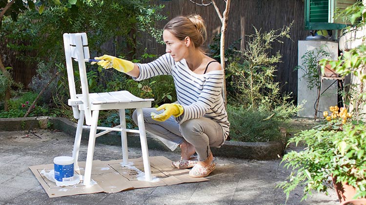 Woman painting a white chair Woman painting a white chair