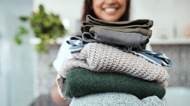 Woman holding a stack of folded clothes Woman holding a stack of folded clothes