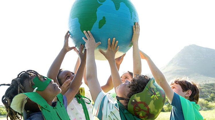 Multiple children holding up an Earth painted ball