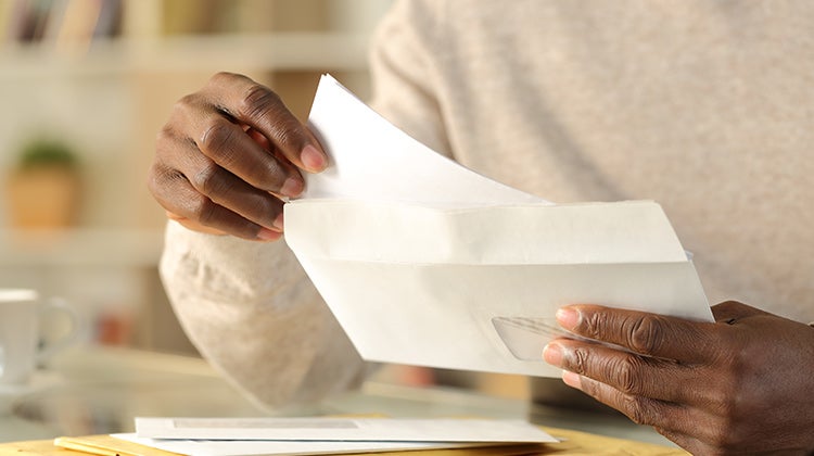 Person putting a document into an envelope Person putting a document into an envelope