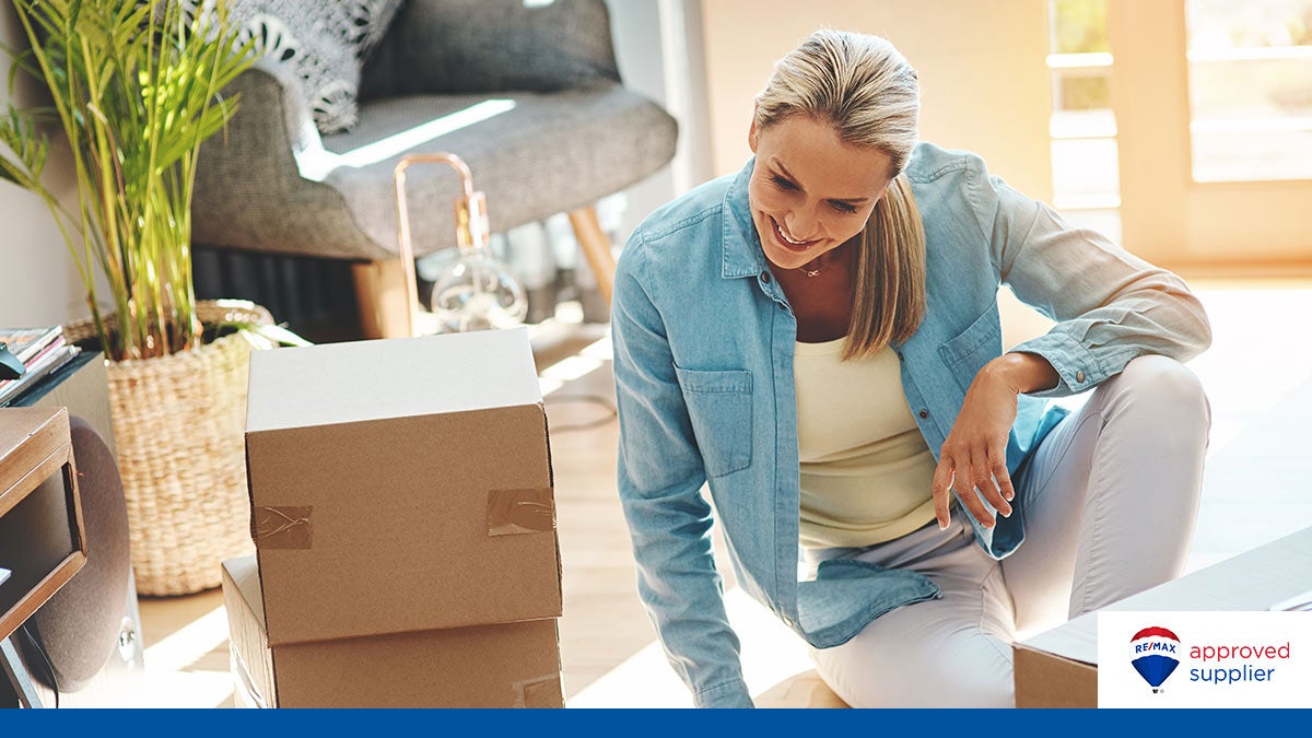 A smiling woman sitting next to moving boxes