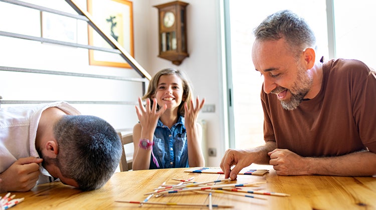 Daughter playing Pick-Up Sticks with her Dads