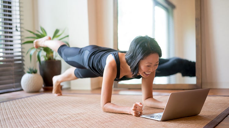 Woman doing an online yoga class in her living room Woman doing an online yoga class in her living room