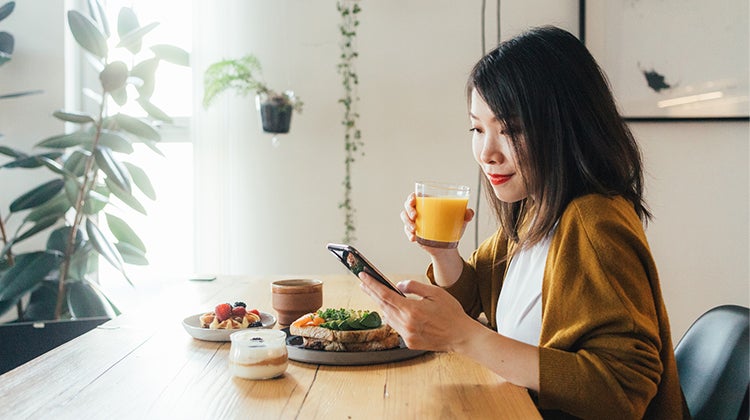 Woman having brunch while looking at her phone Woman having brunch while looking at her phone