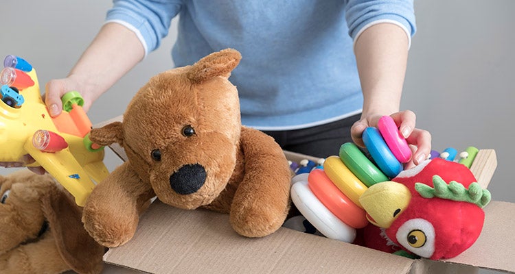 Person putting away old toys in a cardboard box