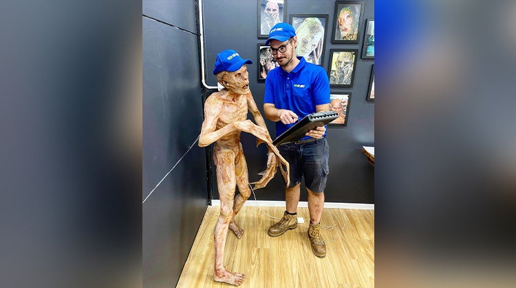 1-800-GOT-JUNK? team member next to zombie statue 1-800-GOT-JUNK? team member next to zombie statue