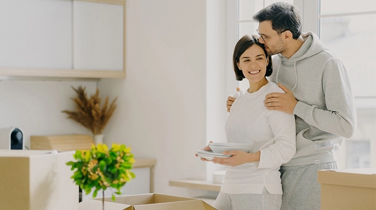 A couple in the kitchen putting plates into boxes