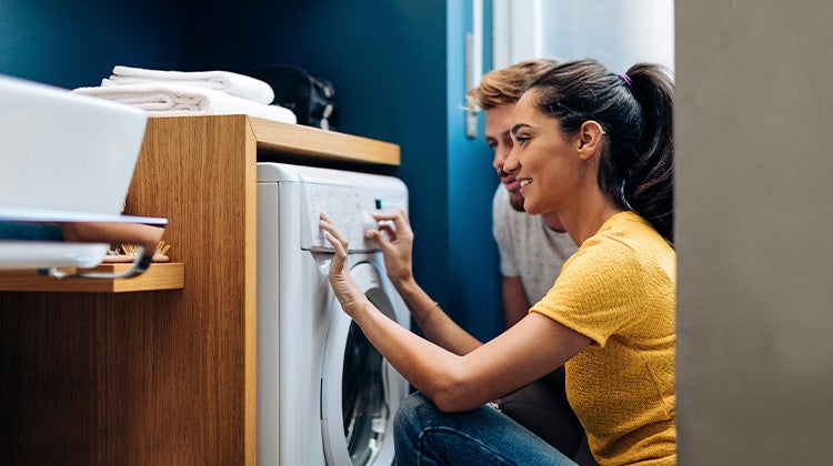 Woman programing her washing machine for a cleaning cycle