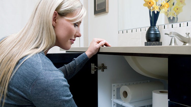 Woman organizing under the sink storage in her bathroom