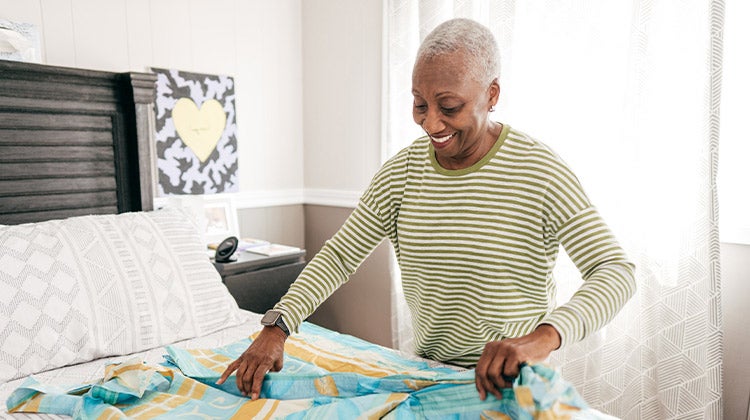 Woman folding a sheet on her bed