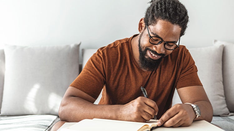 Man writing down a list while sitting at a table