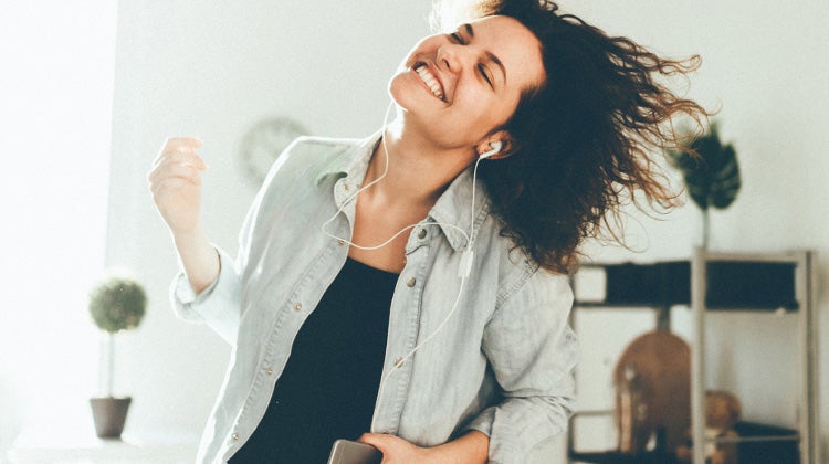 Woman dancing in her home listening to music with earbuds Woman dancing in her home listening to music with earbuds