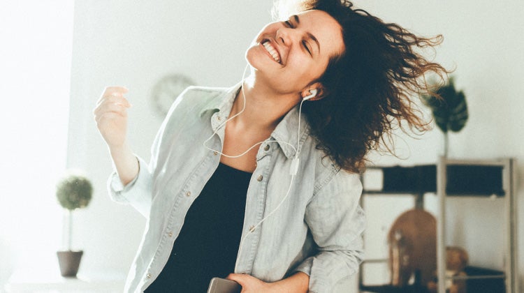 Woman dancing in her home listening to music with earbuds