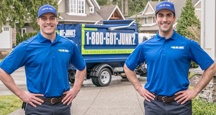 2 TOMs standing in front of a 1-800-GOT-JUNK? truck