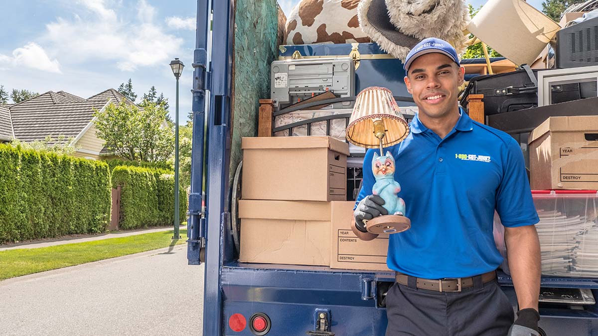 1-800-GOT-JUNK? truck team member posing with a old lamp