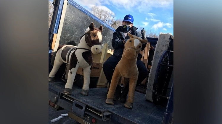 1-800-GOT-JUNK? team member with stuffed horse toys