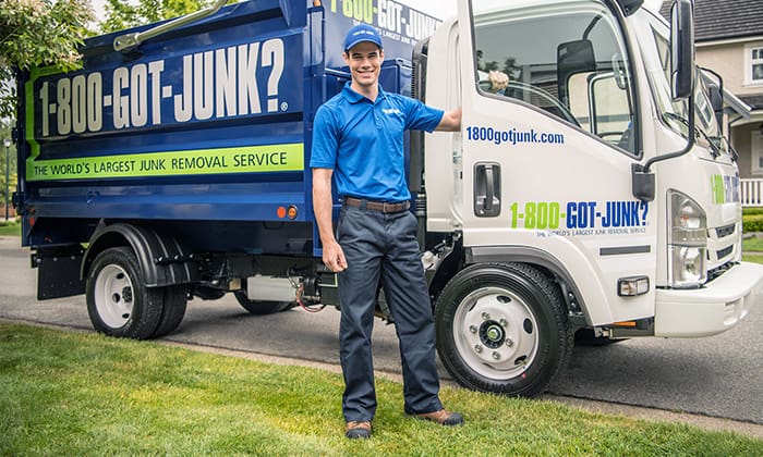 What to do if you miss garbage day 1-800-GOT-JUNK? truck team member standing in front of branded truck in residential neighborhood