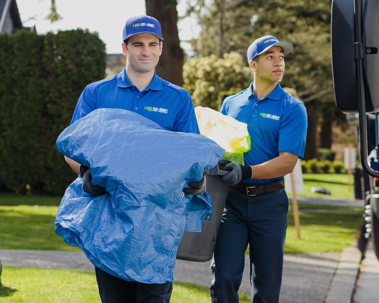 Truck team members carry junk to the truck for disposal