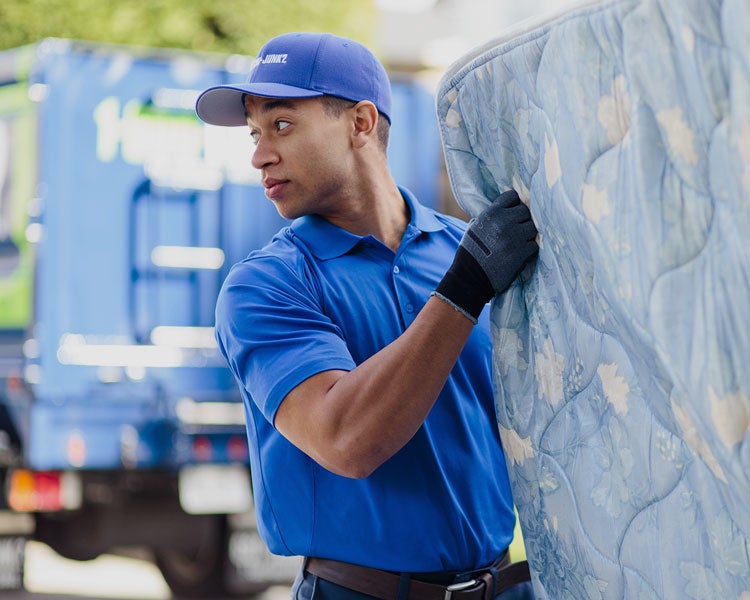 Truck team member carries a mattress to be disposed of