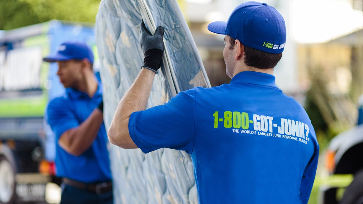 Two 1-800-GOT-JUNK? crew removing a mattress