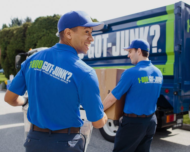 Truck team members carry junk to the truck for disposal