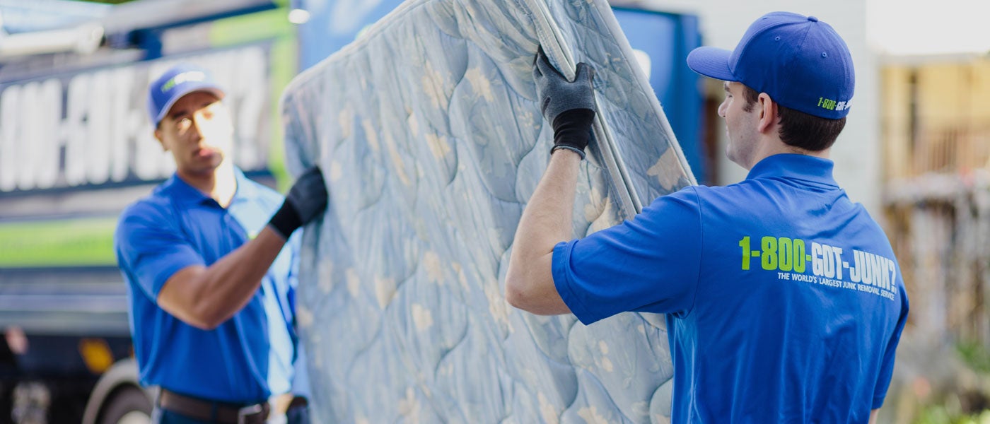 Truck team member carries a mattress to be disposed of