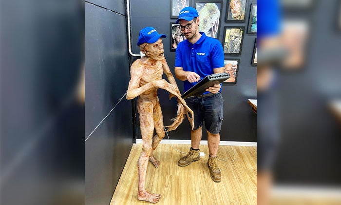 Spooky Junk - Zombie statue A 1-800-GOT-JUNK? Truck Team Member by a zombie statue.